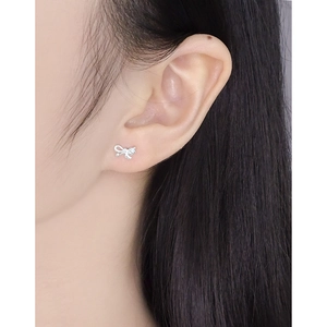Minimalist S925 sterling silver asymmetrical bow earrings shown on model's ear