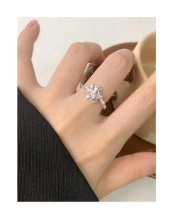 Detailed close-up of a S925 silver bow ring with twisted texture worn on a finger