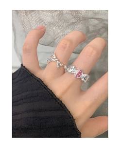 Detail of silver bow rings set featuring a pink gemstone and slim bow design on fingers