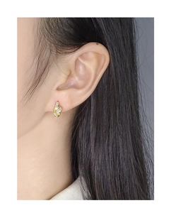 Close-up of golden knot stud earrings featuring rectangular zircons on a model's ear