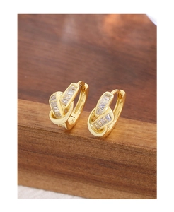 Detailed macro view of gold-plated knot hoop earrings with baguette-cut zircons