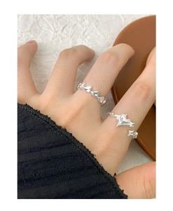 Close-up of S925 sterling silver heart and star rings on finger with soft fabric background