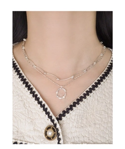 Close-up of double layered silver necklace with floral pendant on elegant tweed outfit
