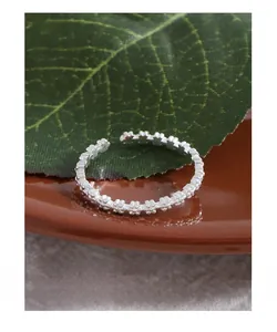 Macro view of S925 sterling silver flower ring with adjustable open band on ceramic plate
