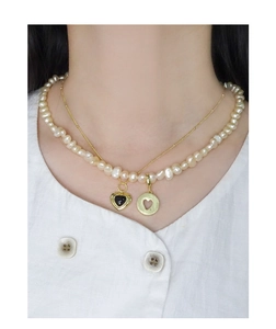 Close-up of double layer pearl necklace with black heart pendant and gold medallion
