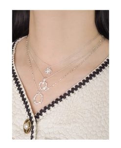 Close-up of S925 silver layered necklaces with floral, heart and oval pendants on model