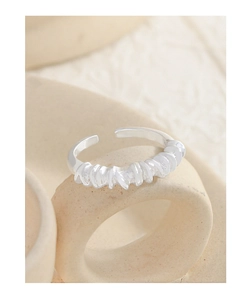 Macro shot of silver twisted rope ring on beige stone texture with a minimalist look