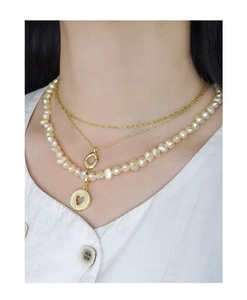 Detail of layered S925 silver gold necklaces with orange-pink pearls and heart pendant