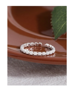 Macro shot of silver daisy flower ring on a ceramic plate with green leaf detail