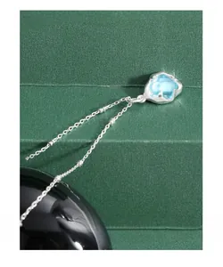Détail macro d'une chaîne perlée en argent S925 et pendentif en cristal bleu clair
