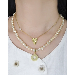 Baroque pink pearl and gold heart pendant layered necklace set worn on a white shirt
