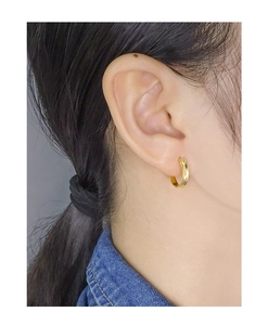 Nahaufnahme einer minimalistischen goldenen Creolen-Ohrring, getragen von einem Modell