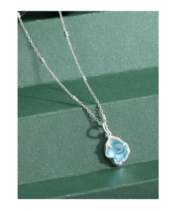 Gros plan du pendentif argenté irrégulier avec cristal bleu clair et chaîne à perles fines