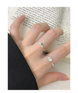 Detail of S925 silver rose flower ring and green gemstone leaf ring on hand