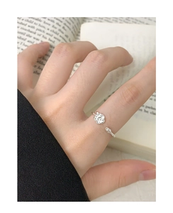 Close-up of S925 silver rose flower open ring worn on hand with vintage book background