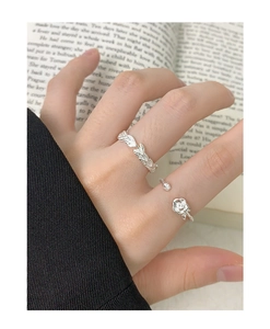 Macro shot of S925 sterling silver rose and leaf rings worn on hand over vintage book pages