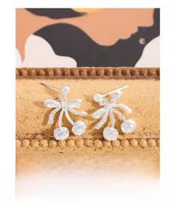 Detailed macro shot of S925 silver cherry bow earrings with hammered texture