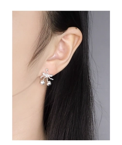 Close-up of S925 silver cherry bow earring worn on ear with polished metallic finish