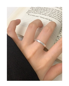 Close-up of minimalist polished silver minimalist ring worn on hand with book background