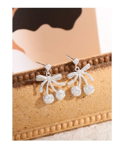 Macro shot of S925 silver cherry bow earrings with textured surface on a vintage stand