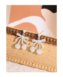 Detailed close-up of S925 silver cherry bow earrings on a vintage display stand