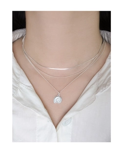 Gros plan sur le collier triple rang en argent S925 avec un pendentif nautile délicat