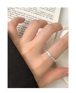 Close-up of a minimalist silver S925 ring on a hand with a warm, aesthetic background