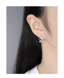 Close-up of elegant silver bow and cherry drop earrings on a model's ear