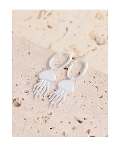 Détail macro des boucles d'oreilles méduse en argent S925 sur fond de pierre naturelle