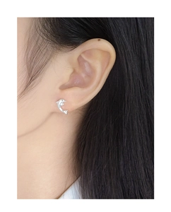 Close-up of a silver dolphin stud earring worn by a model with long black hair