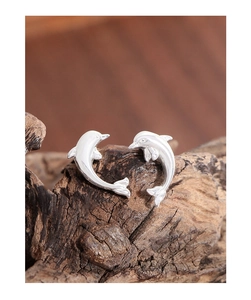 Macro shot of polished S925 sterling silver dolphin stud earrings on a dark wood base