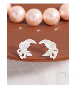 Detailed view of S925 sterling silver moon curved stud earrings on a brown tray