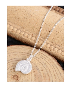 Vue macro d'un collier escargot en argent S925 avec texture spirale sur support bois