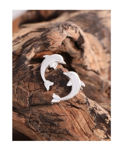 Macro shot of silver dolphin stud earrings on a natural wood surface with fine details