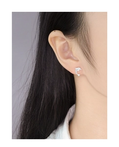 Close-up of a silver dolphin stud earring in S925 silver worn by a female model