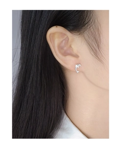 Close-up of a 925 sterling silver dolphin stud earring worn by a model for scale