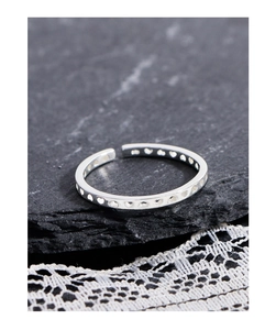Macro shot of 925 sterling silver ring with hollow heart cutouts on a textured surface