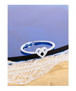 Detail view of S925 sterling silver hollow heart ring with beaded band on beach decor