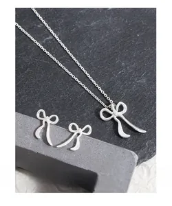 Détail d'un ensemble collier et boucles d'oreilles nœud argenté sur support pierre