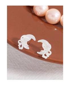 Macro shot of silver crescent earrings on a dark ceramic plate with soft pink pearls