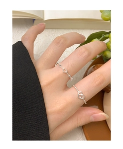 Close-up of S925 sterling silver hollow heart rings on hand with a soft natural aesthetic