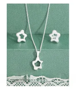 Macro view of S925 sterling silver hollow star necklace and earrings set with white enamel