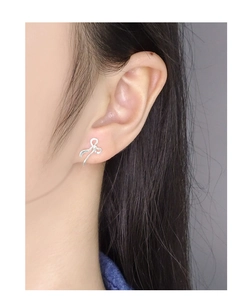 Detailed close-up of a silver S925 ribbon bow earring worn on a female model's ear