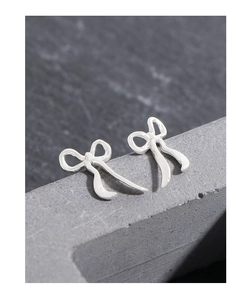 Detailed macro view of S925 sterling silver ribbon bow earrings on a stone surface