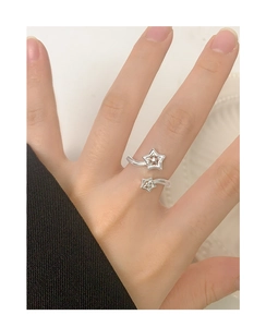 Detail shot of a silver adjustable star ring on finger featuring hollow stars