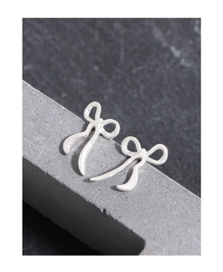 Close-up of elegant S925 sterling silver ribbon bow earrings on a textured stone surface