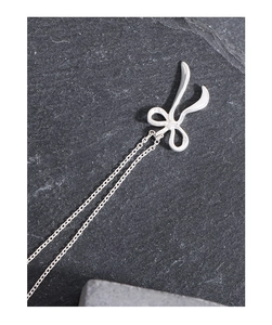 Vue macro d'un collier nœud en argent S925 poli sur un fond de pierre grise texturée