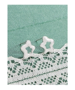 Macro view of minimalist hollow star silver studs with metallic luster on lace