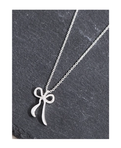 Gros plan du pendentif nœud en argent avec sa chaîne fine sur un fond d'ardoise sombre
