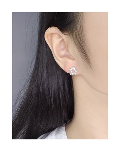 Close-up of minimalist hollow star silver stud earring worn on model's ear
